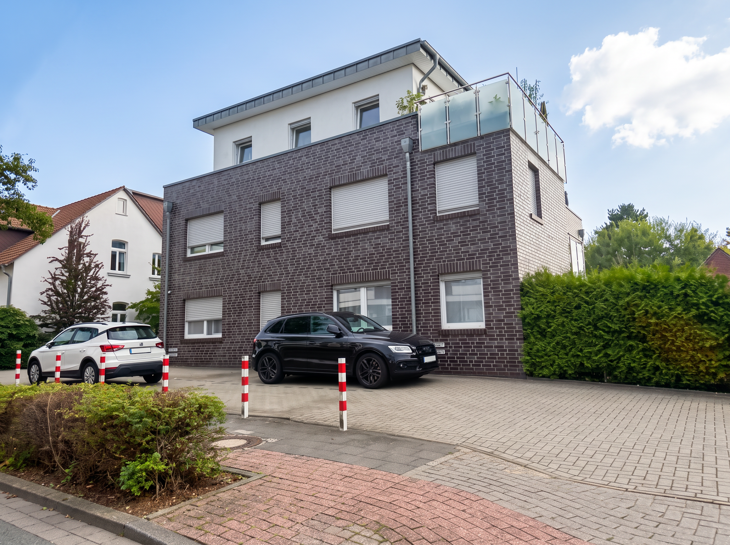 Modernes Mehrfamilienhaus mit dunkler Klinkerfassade, Staffelgeschoss und Dachterrasse