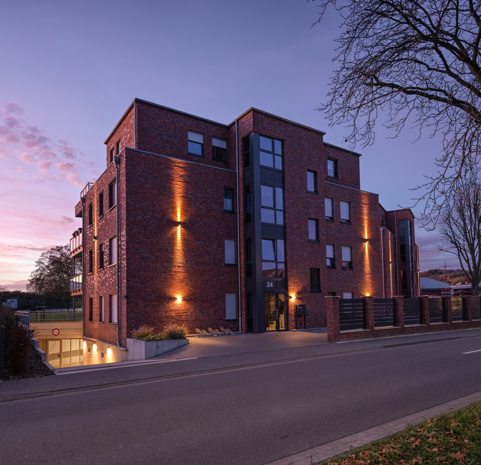 Beleuchtete Klinkerfassade eines Mehrfamilienhauses in der Abenddämmerung
