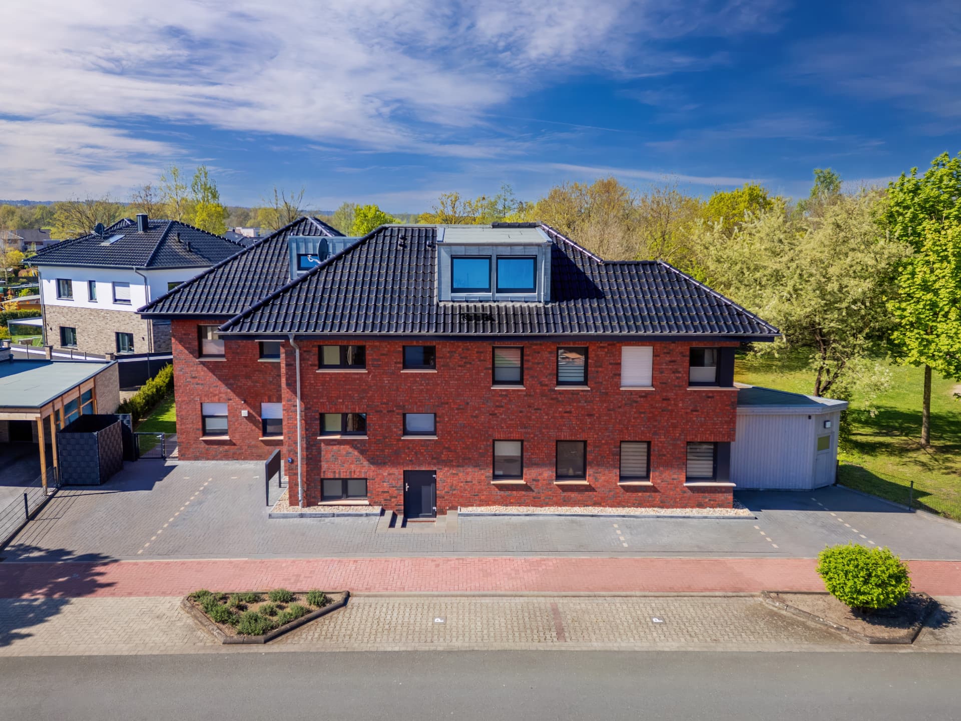 Luftaufnahme eines Mehrfamilienhauses mit Stellplätzen